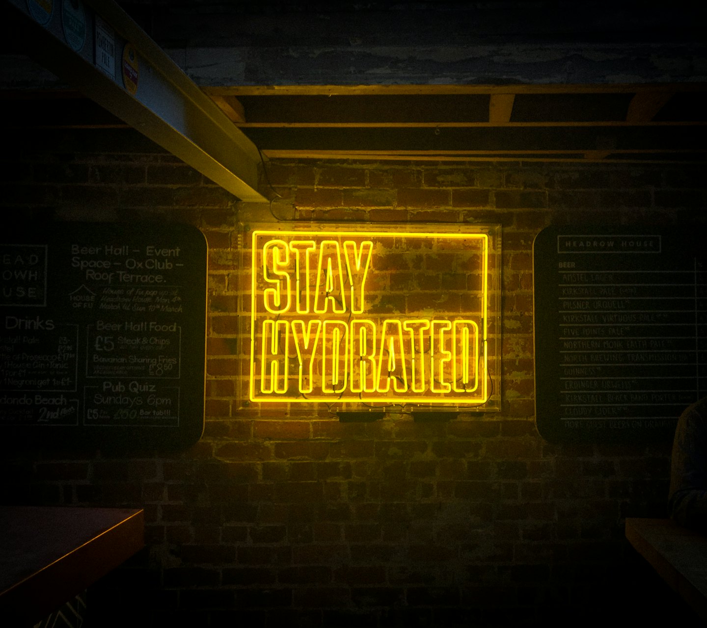 Stay Hydrated yellow neon sign in pub